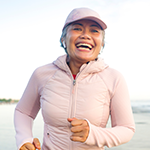 Person jogging along a beach, representing active, healthy living.